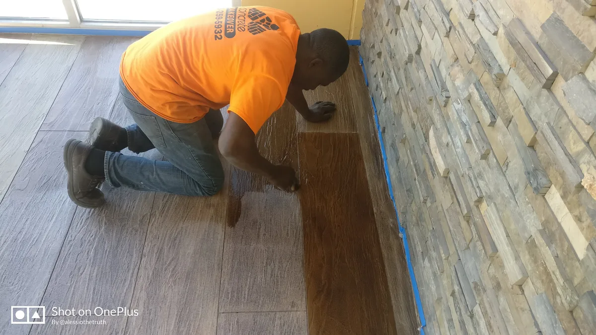 Concrete Makeover crew member staining wood plank overlay floor
