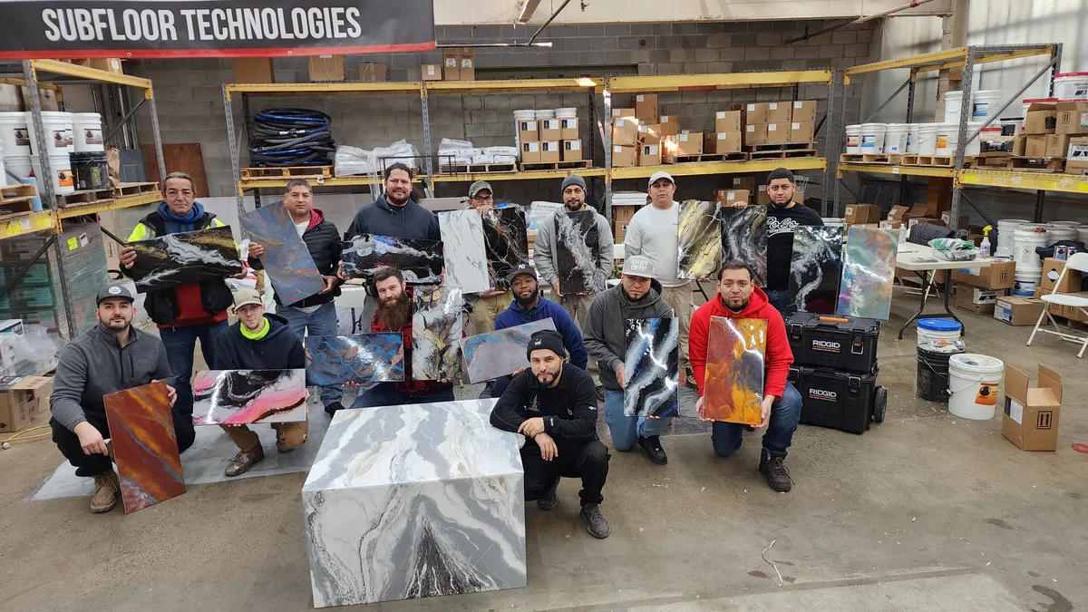 Training class graduates holding their finished decorative concrete sample boards